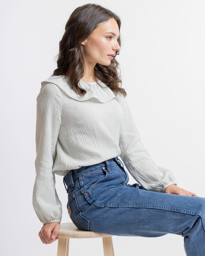 A woman models the blouse pattern while sitting down