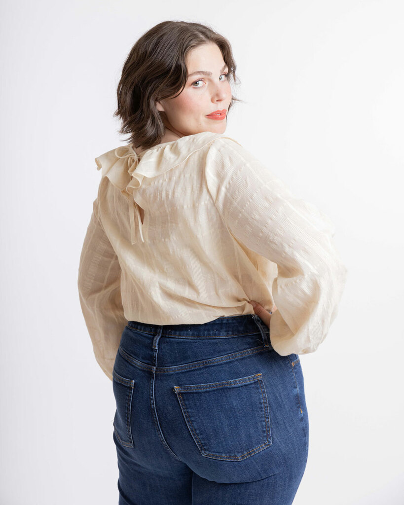 A woman looks over her shoulder while wearing the blouse pattern