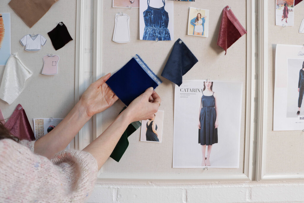 Sarai is reaching to a mood board with velvet swatches and project ideas