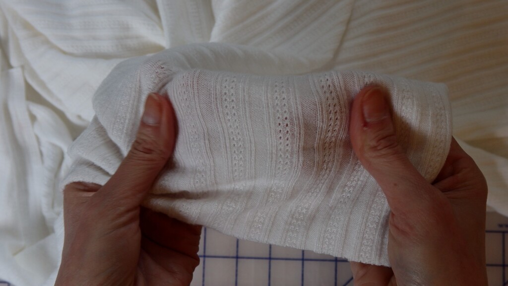 Close-up of white pointelle knit fabric, showing the eyelet texture