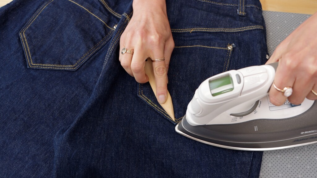 Edgestitch foot and point turner laid out next to a finished jeans pocket with crisp topstitching